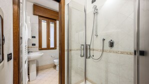 A bathroom with a glass-enclosed shower, a sink, and a toilet. - Emilia Studios 2 (Modena)