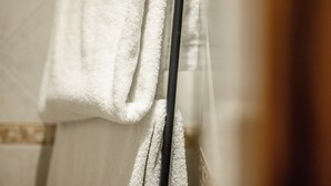 A white towel hanging on a metal rod in a bathroom. - Emilia Studios 2 (Modena)