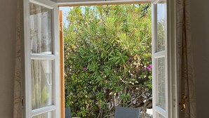 Ein offenes Fenster mit Blick auf eine Terrasse, inklusive Tisch und Stühlen.