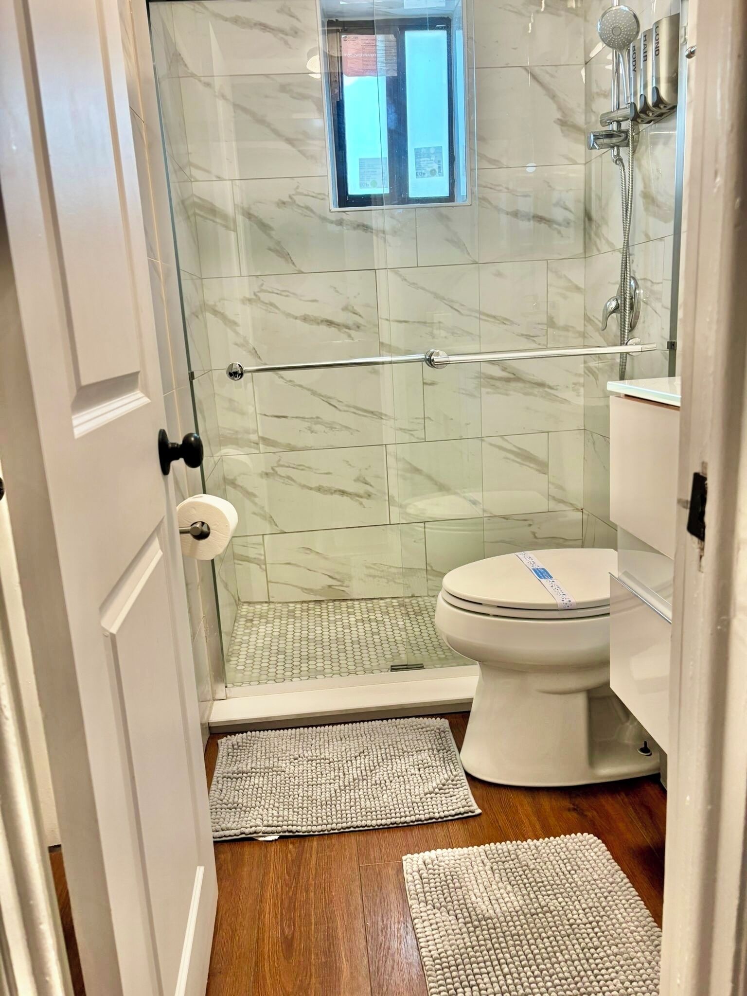 Een badkamer met een douchecabine van glas, een toilet en een wastafel.