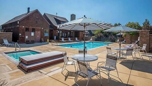 A pool area with lounge chairs and umbrellas, a brick building, and a clear blue sky. - Beautiful 2-bedroom townhome with Patio, WiFi, AC (Sisters)