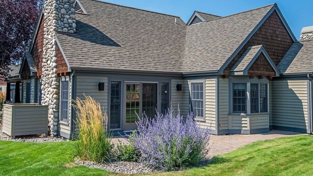 A modern house with a stone chimney, large windows, and a well-maintained garden. - Beautiful 2-bedroom townhome with Patio, WiFi, AC (Sisters)