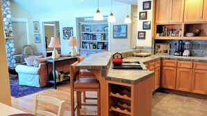 A spacious kitchen with wooden cabinets, a built-in wine rack, and a dining area with a table and chairs. - Beautiful 2-bedroom townhome with Patio, WiFi, AC (Sisters)