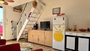 Un espacio habitable pequeño con cocina, comedor e una escalera.