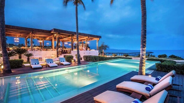 A poolside area with lounge chairs and a covered seating area, overlooking a body of water. - Luxury Condo at Surf Residence with Ocean Views (Punta Mita)