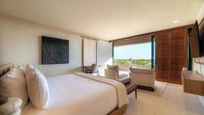 A modern bedroom with a large bed, a seating area with a view, and a flat-screen TV. - Luxury Condo at Surf Residence with Ocean Views (Punta Mita)
