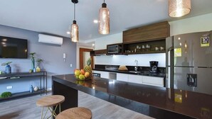 A modern kitchen with a central island, stainless steel appliances, pendant lighting, and a fruit bowl. - Villa del Peñon 301 - 2-Bed With Nice Balcony (Cali)