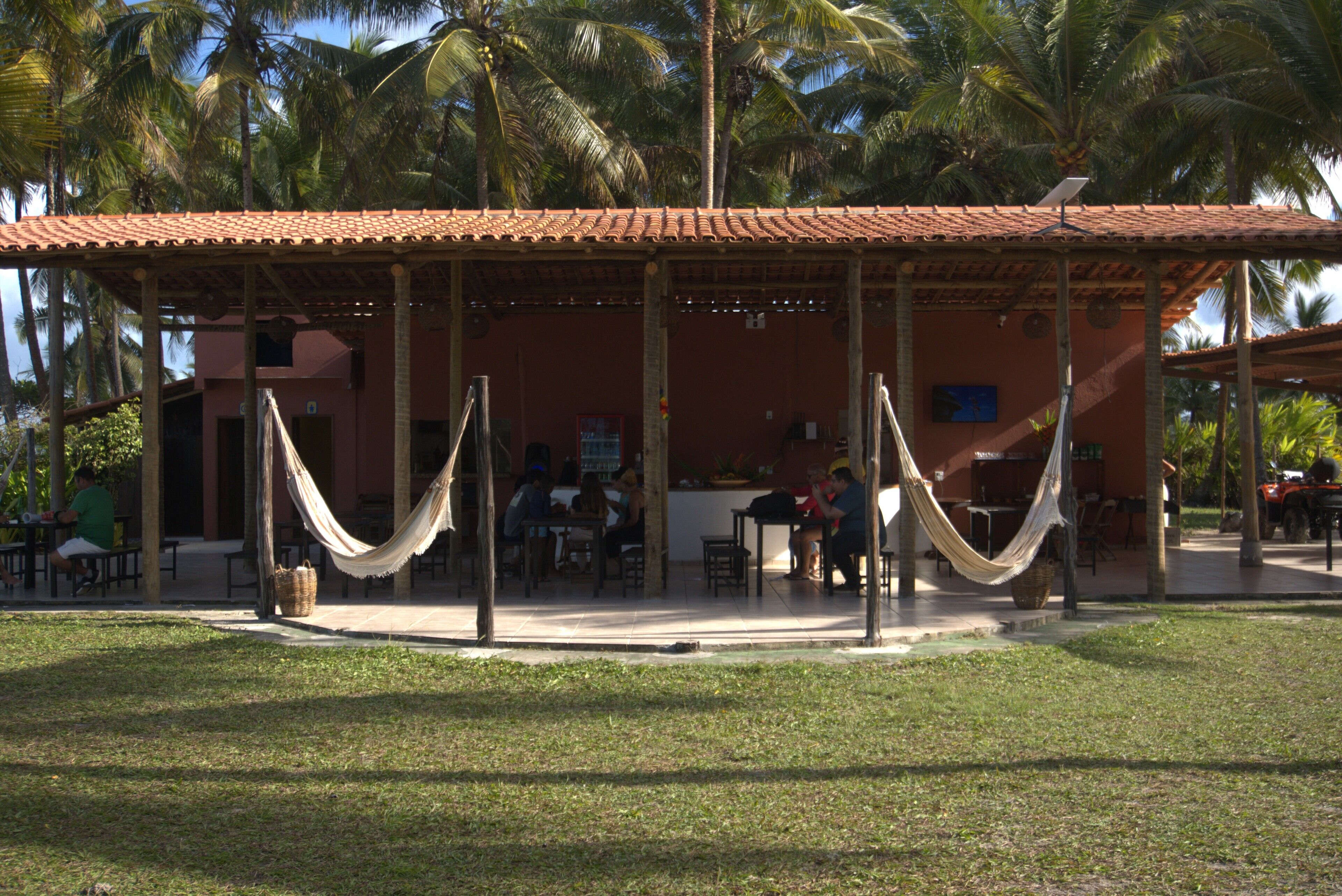 A covered outdoor seating area with hammocks, tables, and chairs.
