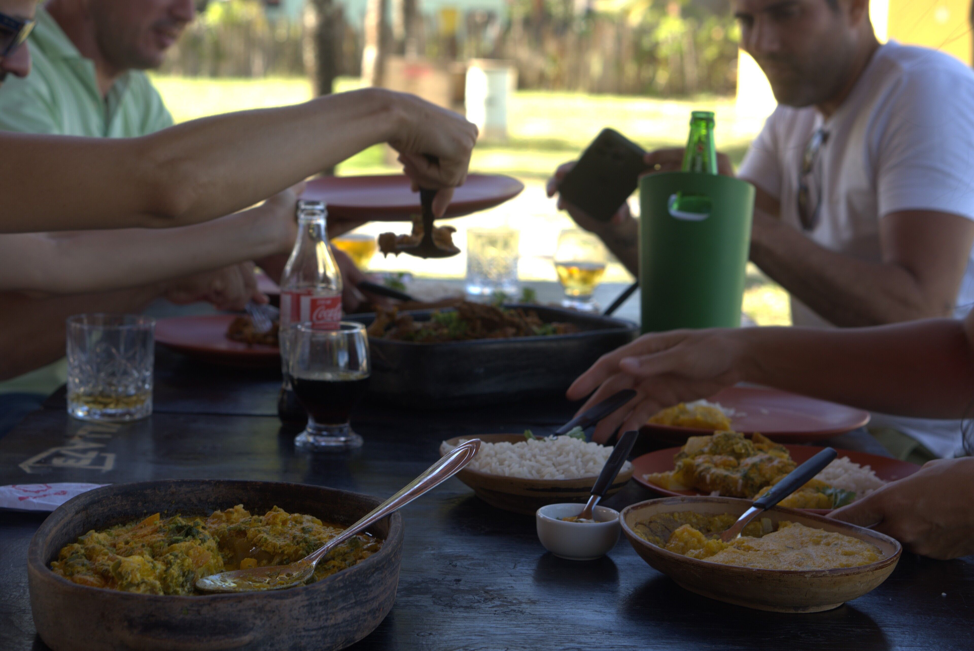 Een groep mensen dineert aan een tafel met diverse gerechten en drankjes.