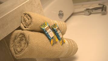 A bathroom with a bathtub, a towel, and two tubes of lotion.