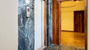 Un mur de marbre, une porte en bois et un couloir au plancher de bois.