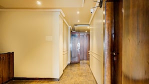 Un couloir au sol en bois et aux portes en bois, qui mène à une pièce dotée d’une porte en bois.