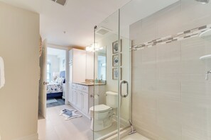 Un baño moderno con cabina de ducha de vidrio, inodoro y lavabo con encimera.