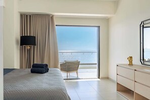 Relax in a spacious room with a large bed, side table, and stunning sea views through a large sliding door.