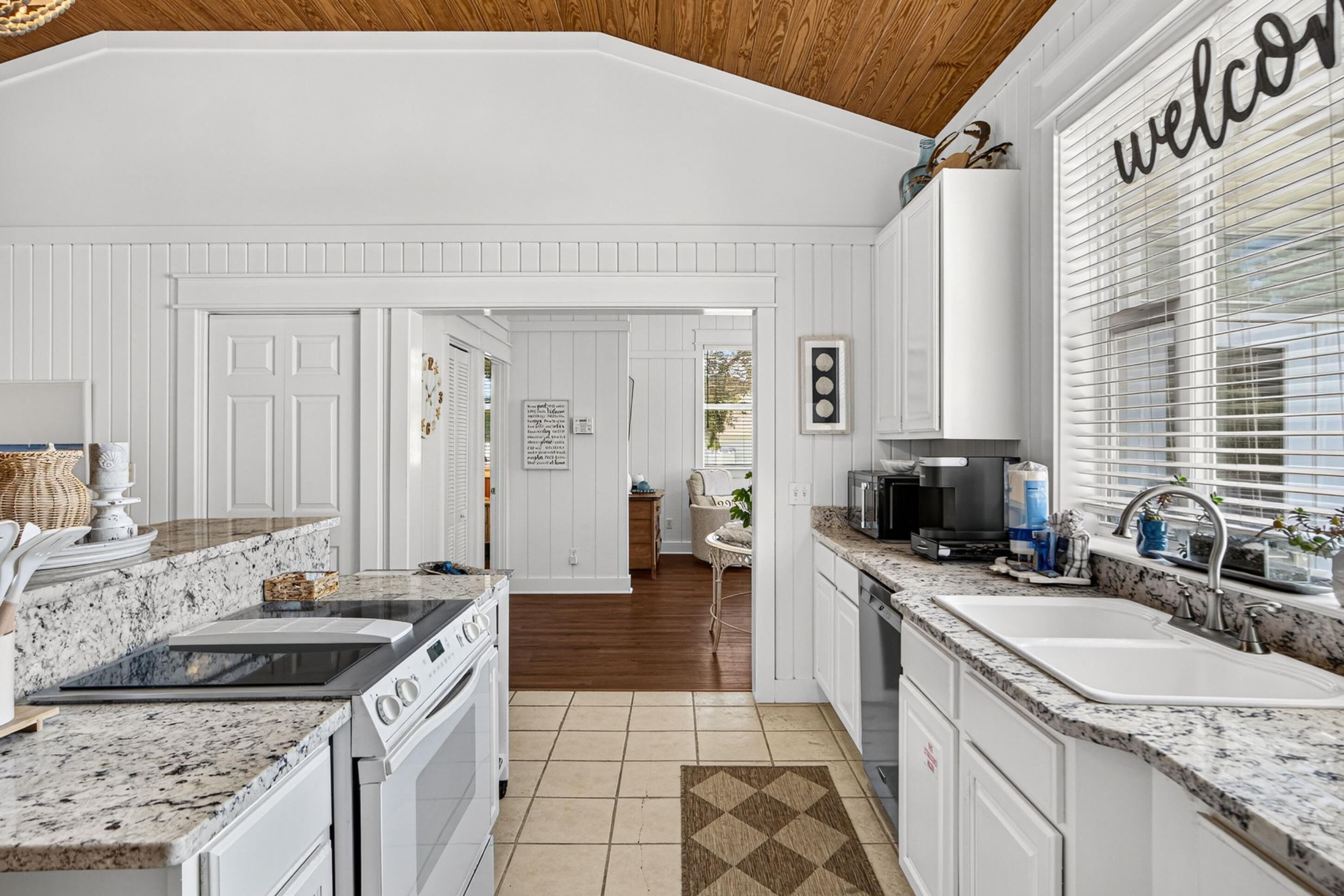 A kitchen with white cabinetry, a stove, and a sink.