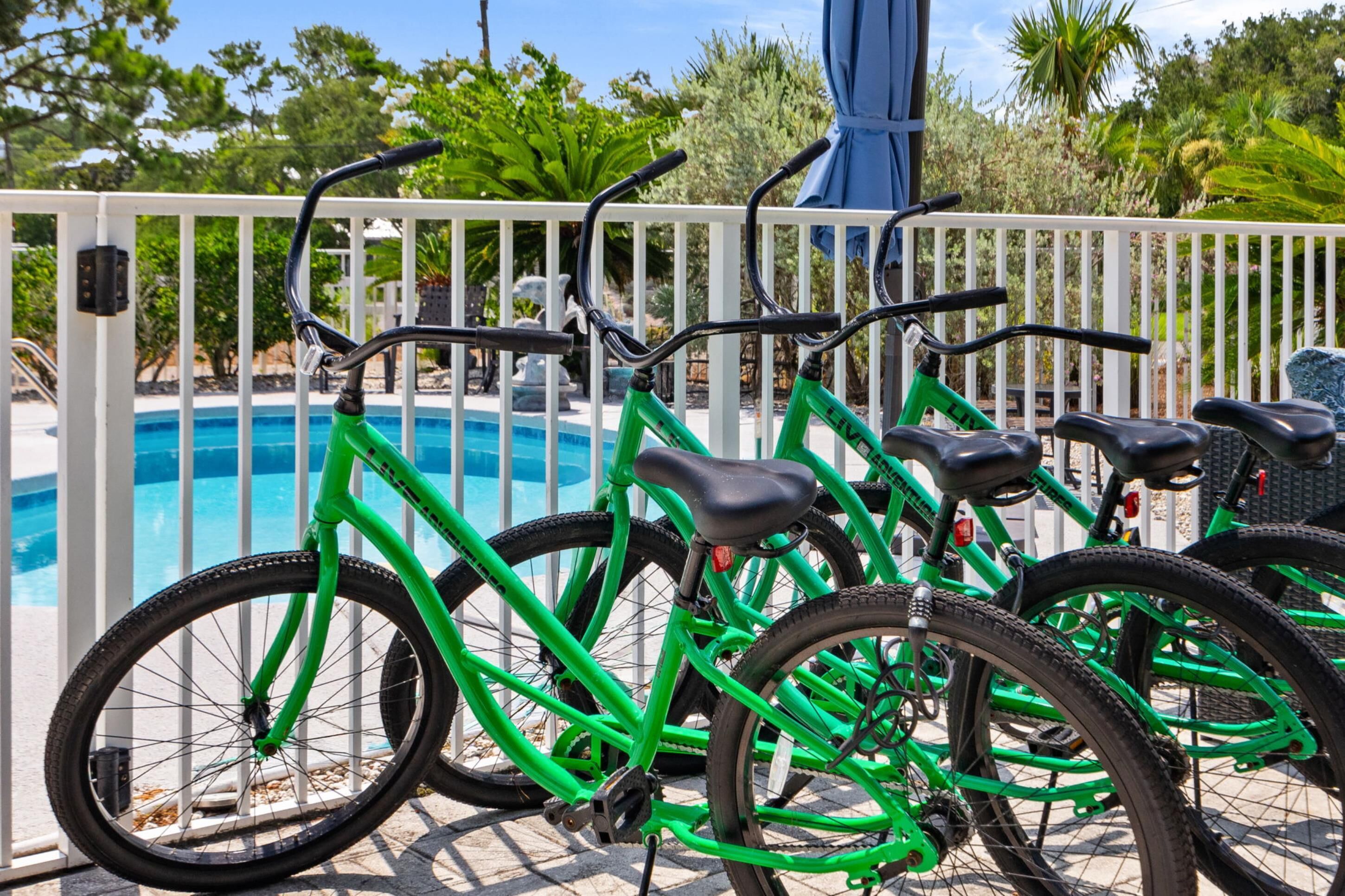 A poolside area with bicycles parked near a white fence.