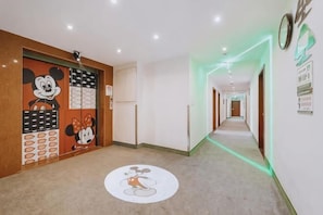 A hallway with a Mickey Mouse mural on the left wall, a circular Mickey Mouse design on the floor, and a green-lit corridor on the right. - HaoTai Hotel (Shanghai Pudong Airport, Wildlife Park) (Shanghai)