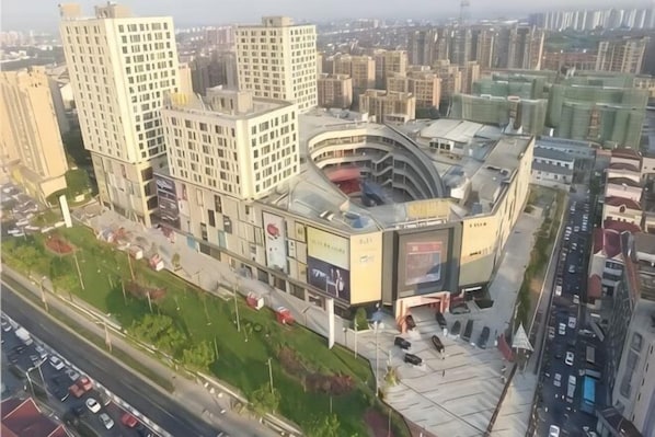 A multi-story building with a curved facade, large signage, and a parking area. - HaoTai Hotel (Shanghai Pudong Airport, Wildlife Park) (Shanghai)