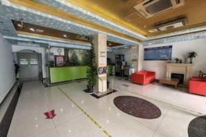 A hotel lobby with a reception desk, a fireplace, red seating, and a large poster on the wall. - HaoTai Hotel (Shanghai Pudong Airport, Wildlife Park) (Shanghai)