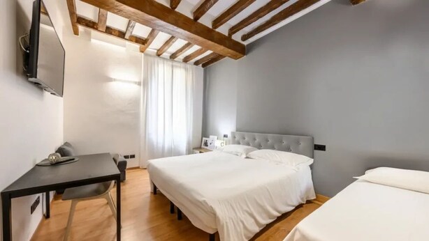A bedroom with a bed, a desk, and a TV mounted on the wall. - Emilia Studios 3 (Modena)