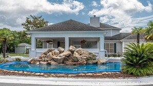 Une maison avec une piscine, entourée de rochers et de palmiers.