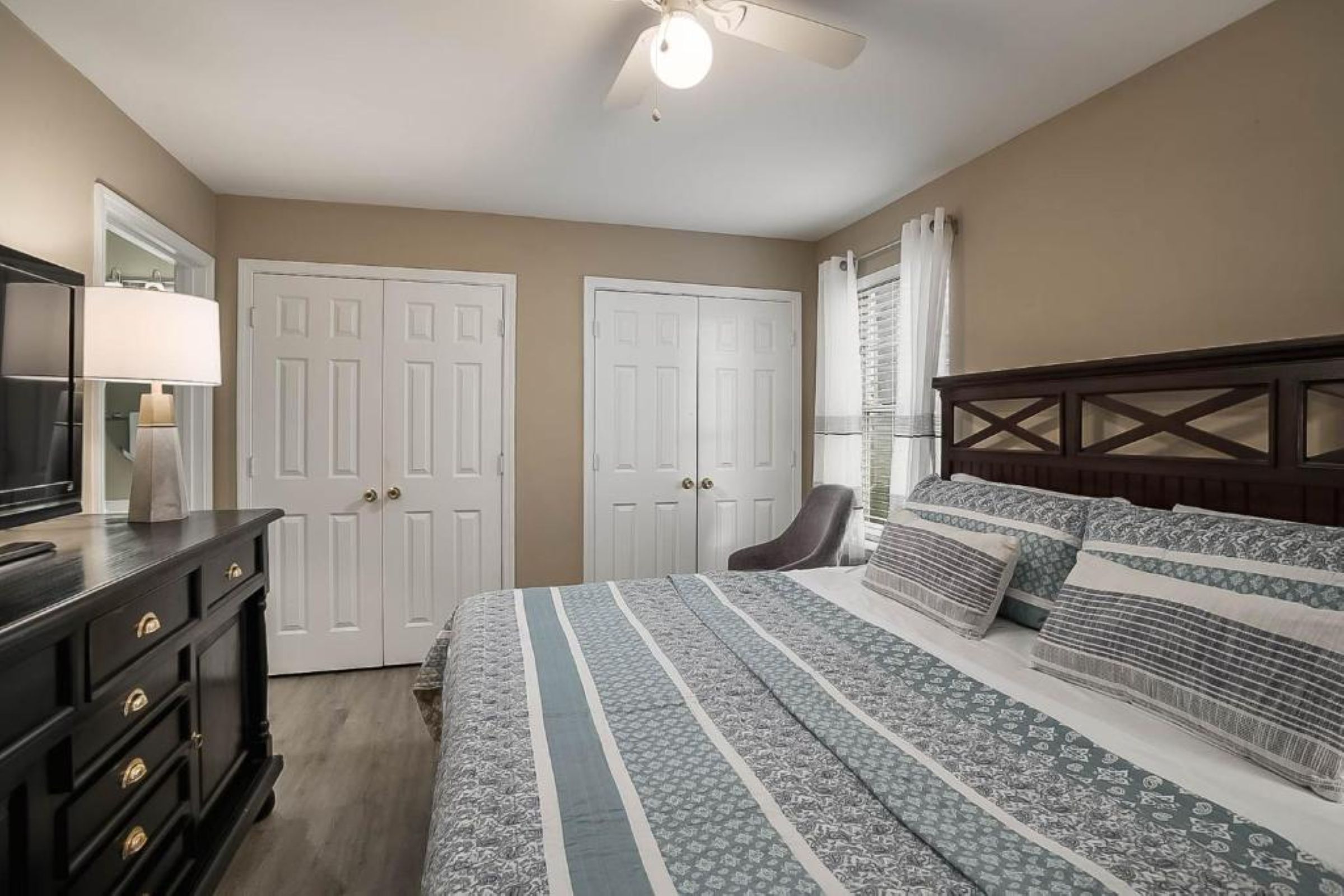 A bedroom with a bed, dresser, and a ceiling fan.