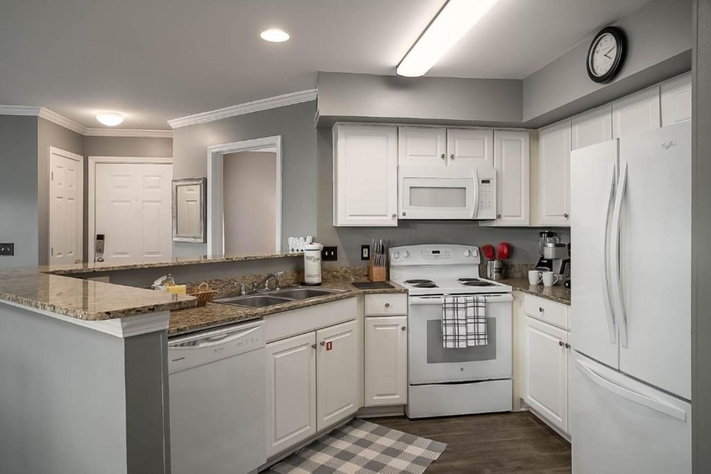 Una cocina moderna con armarios blancos, microondas integrado, estufa y refrigerador.