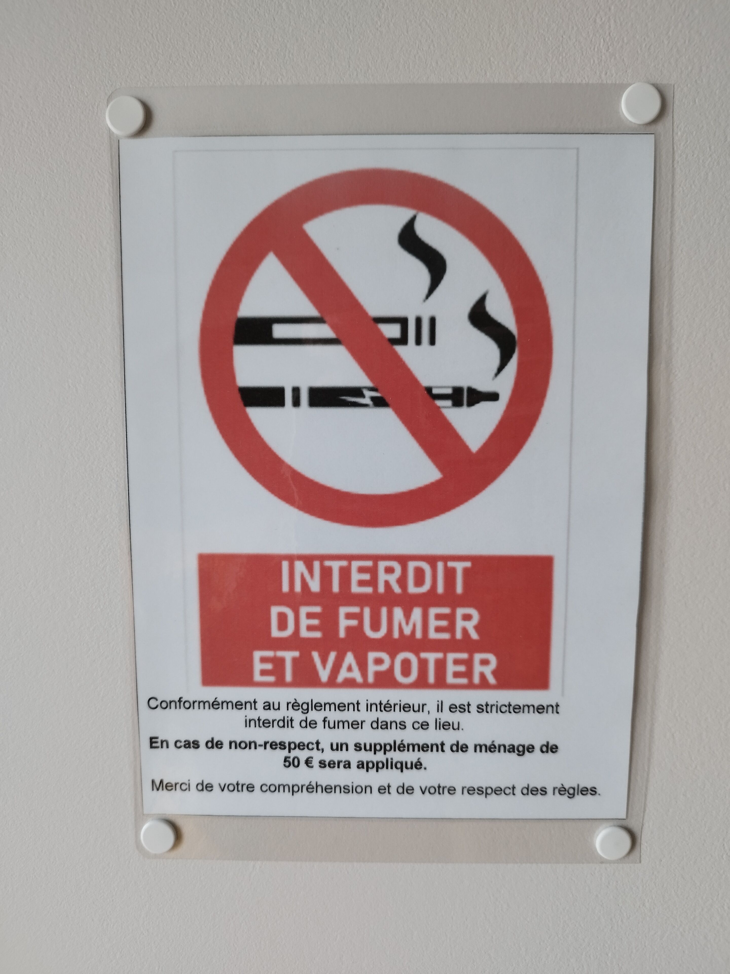 Un panneau « défense de fumer » avec un texte en français mettant en garde contre le tabagisme et le vapotage, ainsi qu’une mention indiquant qu’une amende est prévue en cas de non-respect de cette interdiction.