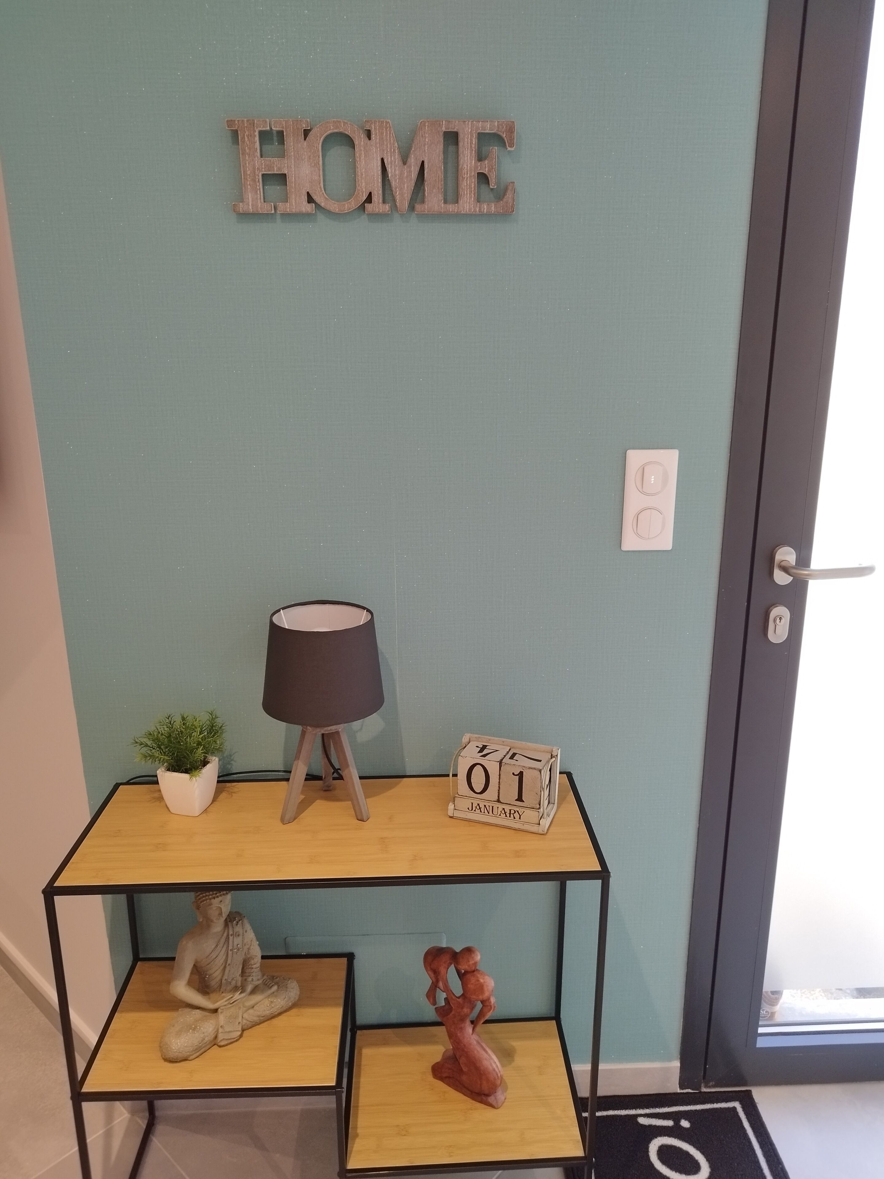A wooden console table with a potted plant, a lamp, and a date block.