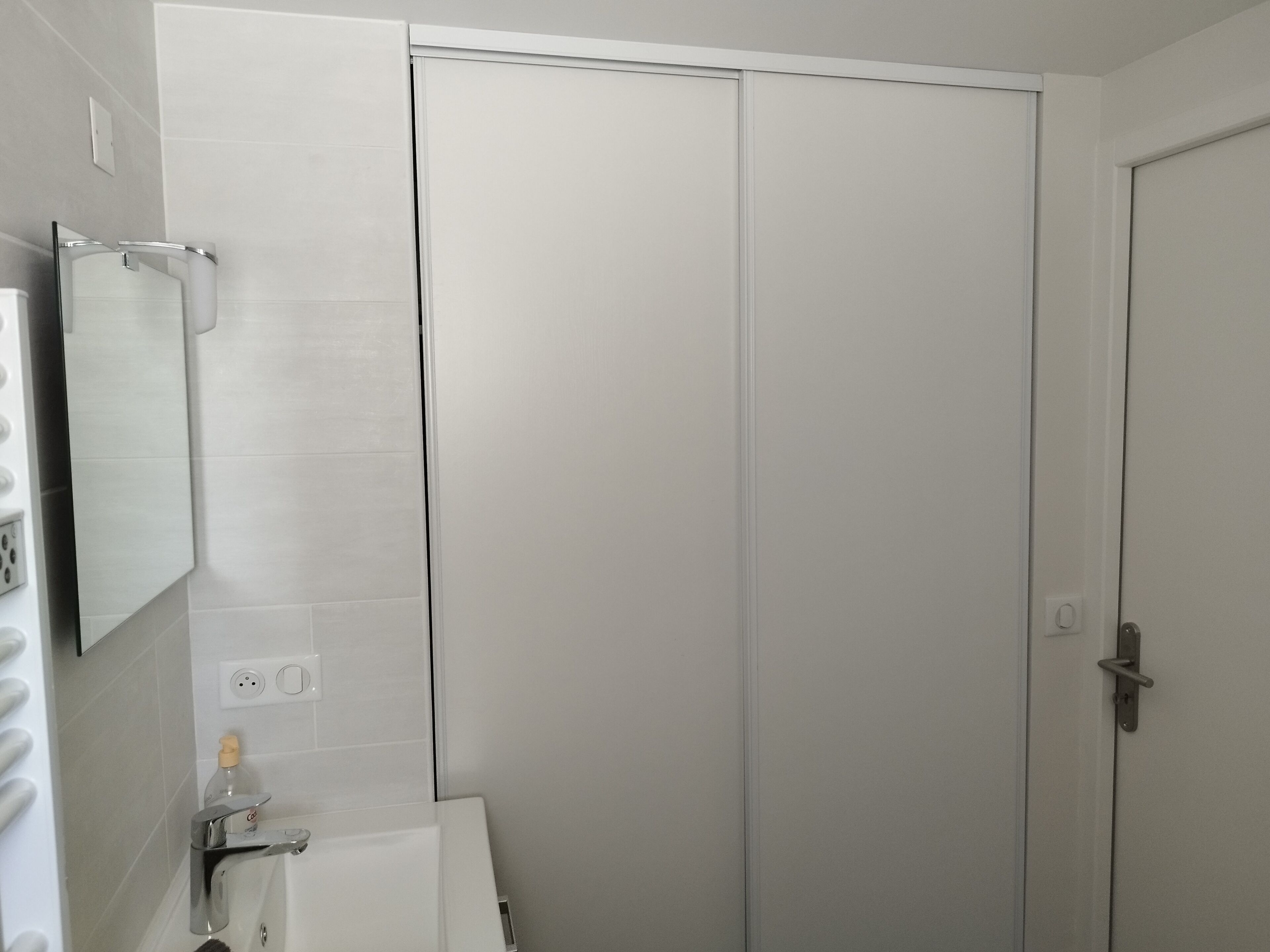 A bathroom with a white bathtub, a mirror, and a toilet.