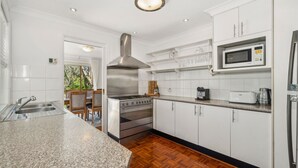A modern kitchen with white cabinets, stainless steel appliances, and a herringbone wood floor.