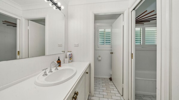 A bathroom with a white vanity, a large mirror, and a shower area with a door leading to a balcony.