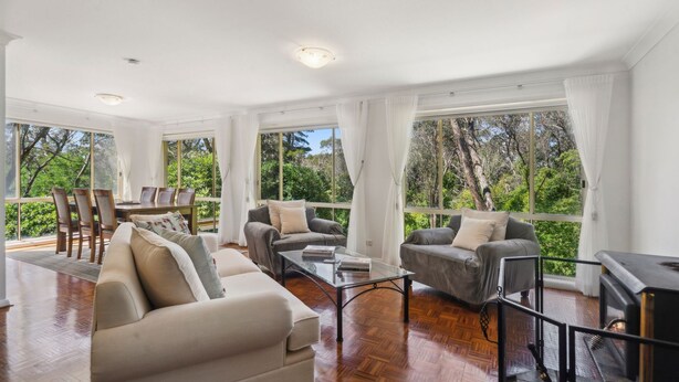 A spacious living room with a large window, a dining area, and a sofa.