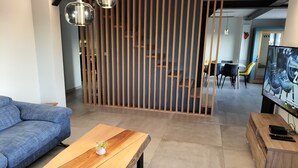 A modern living room with a blue sofa, a wooden coffee table, and a TV stand. - Large 8-person house with sauna, terrace and garden close to Colmar (Sainte-Croix-en-Plaine)