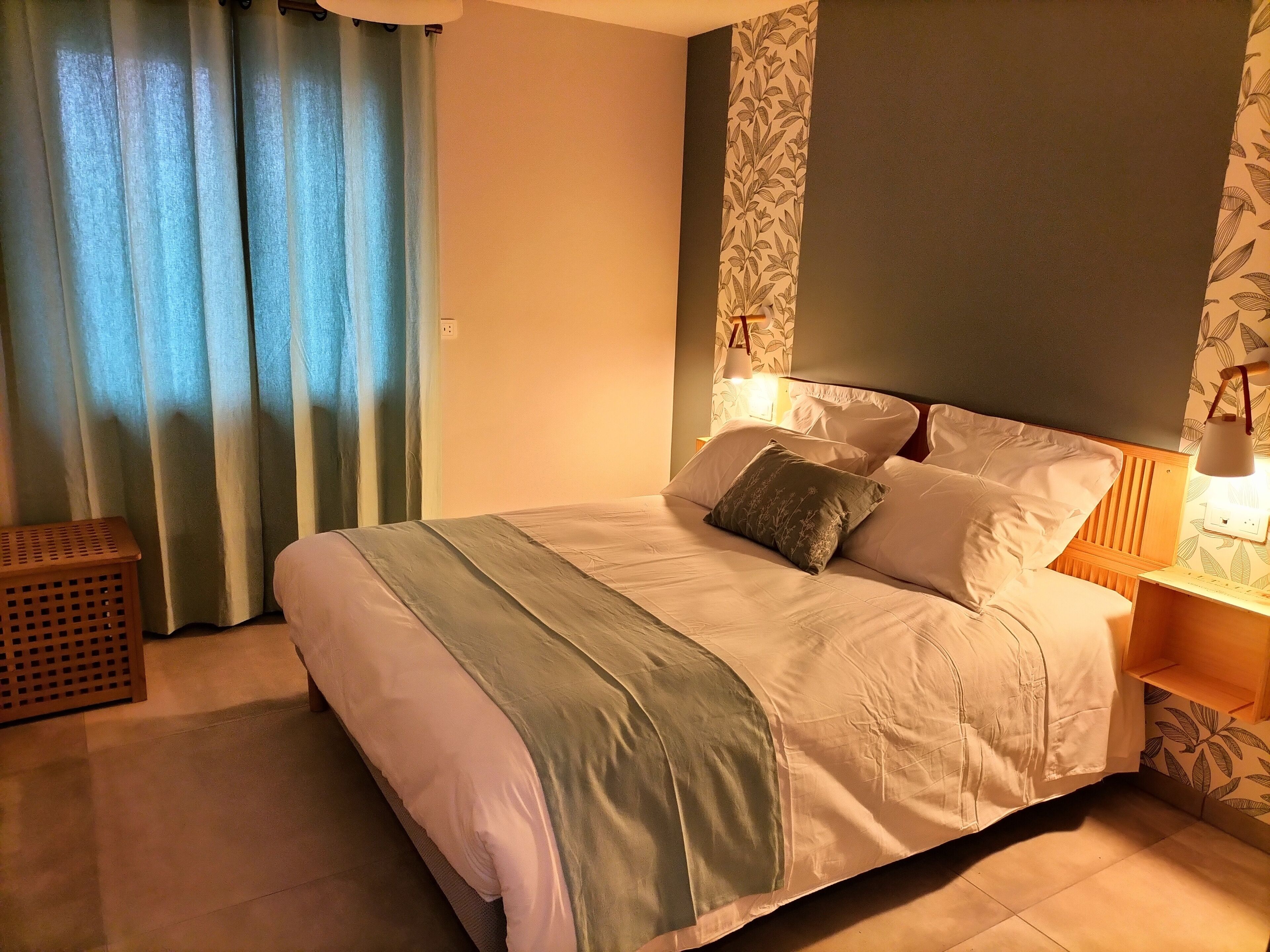 A neatly made bed with a headboard, two bedside lamps, and a patterned wall.