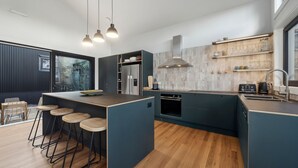 Una cocina moderna con una isla central, taburetes de bar y horno empotrado.