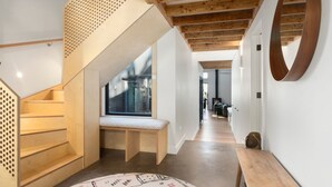 Un interior moderno con una escalera de madera, un banco y vistas al exterior.