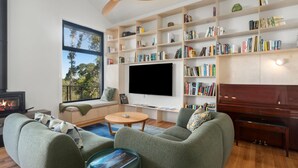 Una sala de estar moderna con chimenea, asientos cómodos, una amplia estantería y un televisor de pantalla plana.