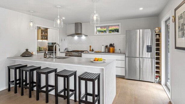 A modern kitchen with a central island, bar stools, stainless steel appliances, and pendant lighting. - Spacious family home in Meadowbank| by Furnished Rentals (Auckland)