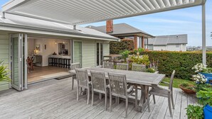 A covered patio with a dining table and chairs, a kitchen area, and a view of neighboring houses. - Spacious family home in Meadowbank| by Furnished Rentals (Auckland)