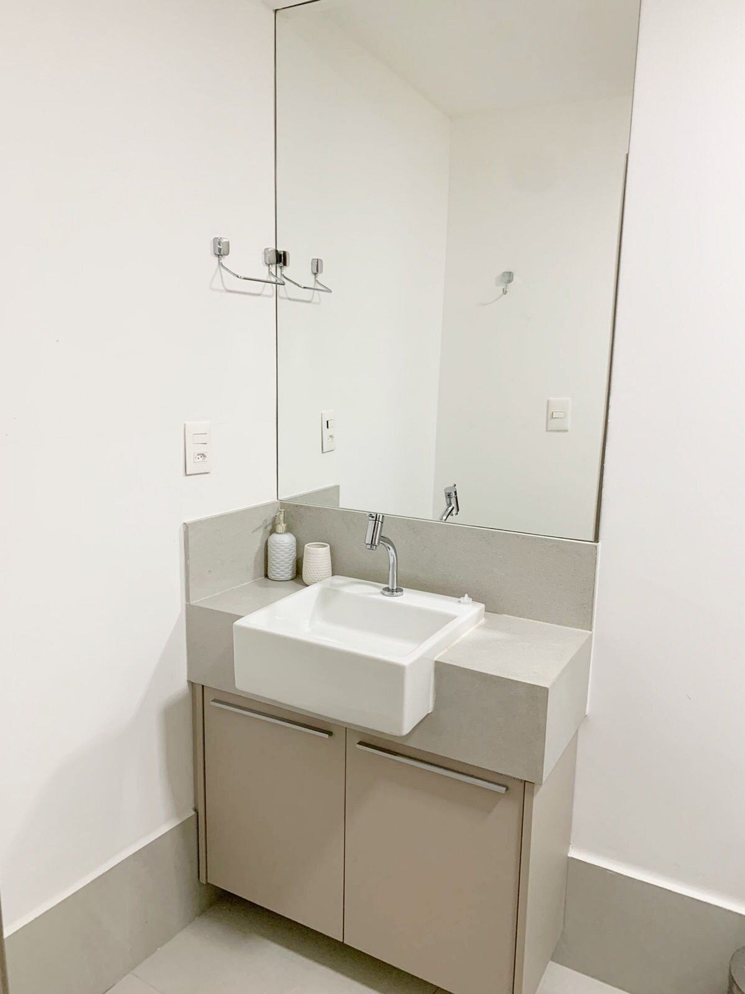 Casa de banho moderna com uma sanita branca, um espelho grande e um porta-toalhas.