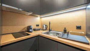 Eine moderne Küche mit dunklen Schränken, einer Holz Arbeitsplatte, einer Edelstahl-Spüle und einer Kaffeemaschine.
