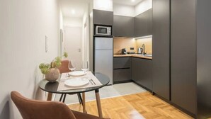 Eine kompakte Küche mit modernen Geräten, ein Essbereich mit Tisch und Stühlen sowie ein kleiner Blumentopf.