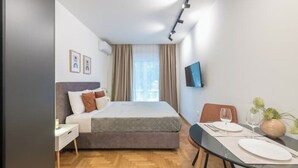Ein modernes Schlafzimmer mit einem Bett, einem Nachttisch und einer Essecke mit Tisch für zwei Personen.