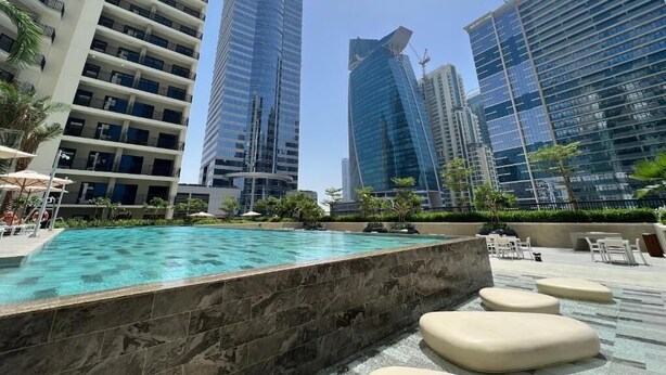 A modern hotel pool area with a clear view of surrounding high-rise buildings. - 1BHK in Business Bay close to metro  (Dubai)
