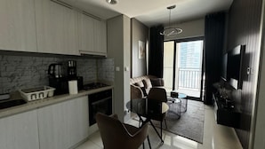 A modern kitchen with a dining area, a sofa, and a balcony with a view. - 1BHK in Business Bay close to metro  (Dubai)