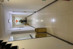A corridor with a reflective floor, a plant, and a door at the end. - Rongyue Hostel (Shanghai)