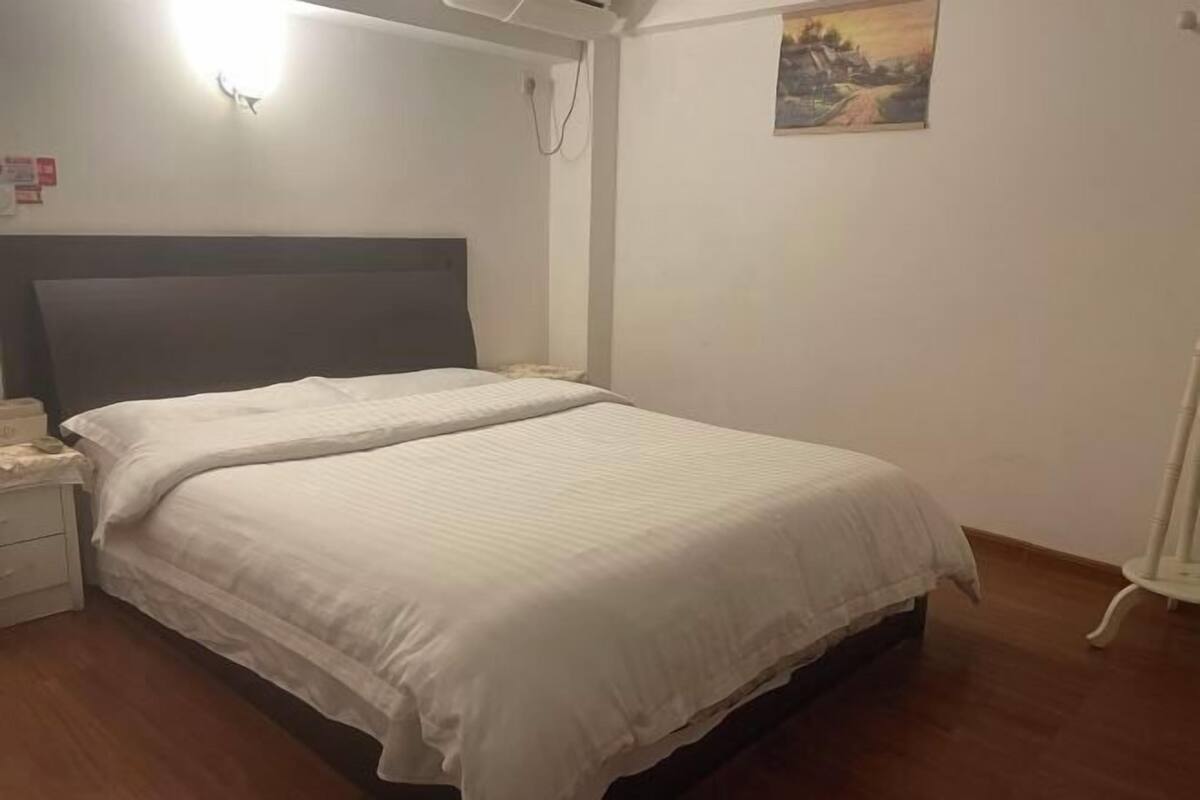A bedroom with a bed, bedside table, and a wall-mounted light fixture.