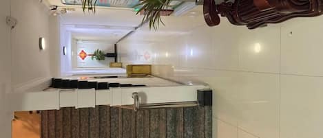 L’intérieur d’un hôtel, avec un escalier moderne, un comptoir d’accueil et une vue sur le hall d’entrée.