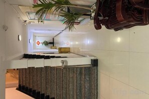 A hotel corridor with a reception desk, a staircase, and a plant. - Rongyue Hostel (Shanghai)